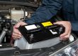 Image of a man putting in a restored battery into a car. The battery was restored using high impact battery restoration.