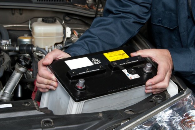 Image of a man putting in a restored battery into a car. The battery was restored using high impact battery restoration.